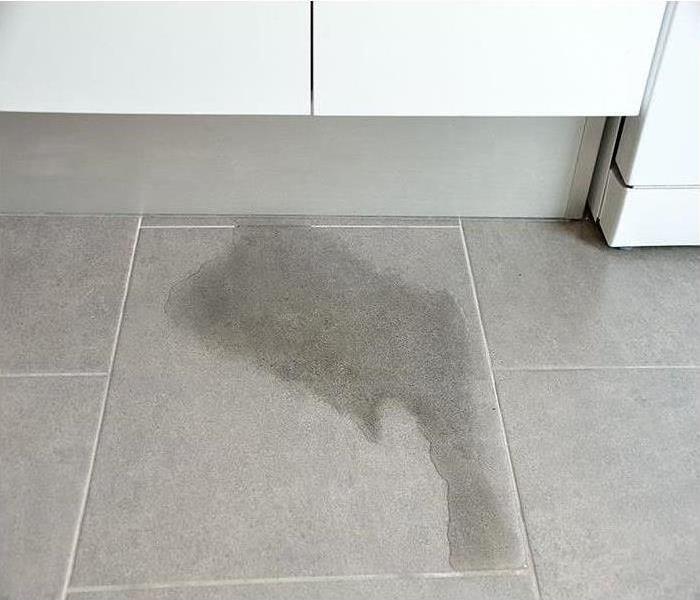 Water damage on a tile floor by a kitchen cabinet